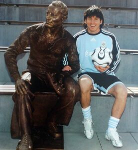 Lio Messi junto a la estatua de Adi Dassler, por hectorlopezsanson bajo CC BY-NC-SA 2.0